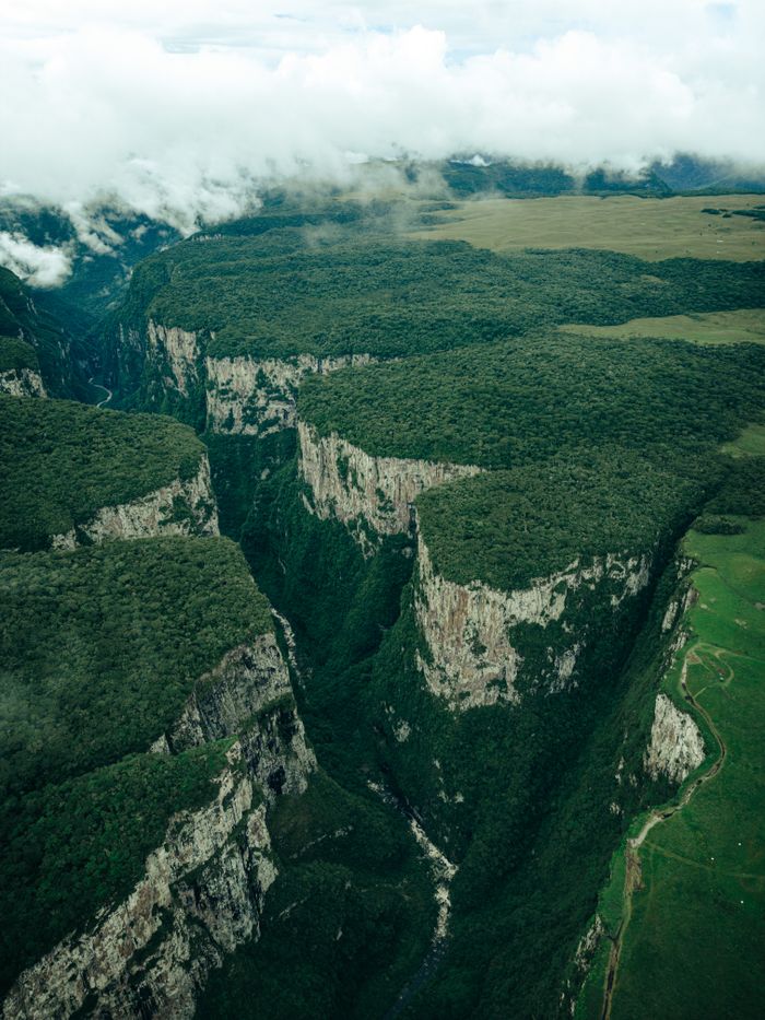 Dramatic aerial view of canyons with lush vegetation in Cambará do Sul, Brazil, showcasing stunning natural formations.