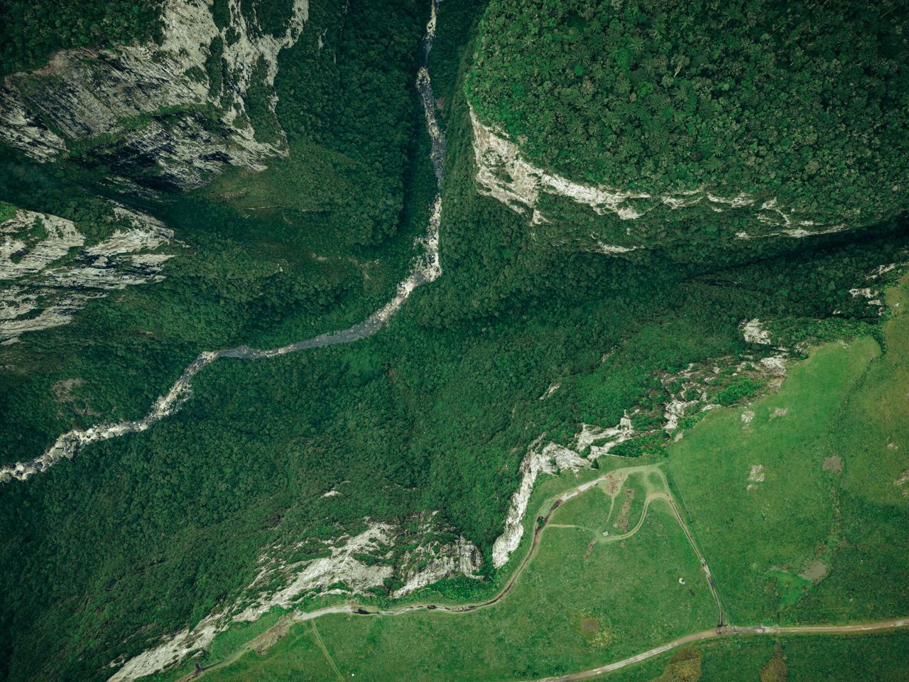 Breathtaking aerial shot of lush canyon landscape in Cambará do Sul, Brazil, showcasing dense forests and rugged rock formations.